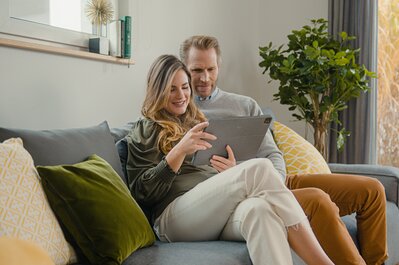 Kanapén egy tableten tartalmakat böngésző pár